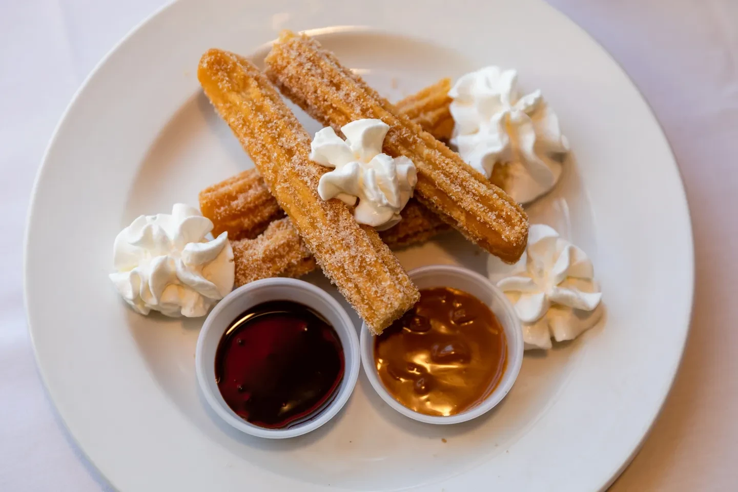 Churros with whipped cream, chocolate and dulce de leche