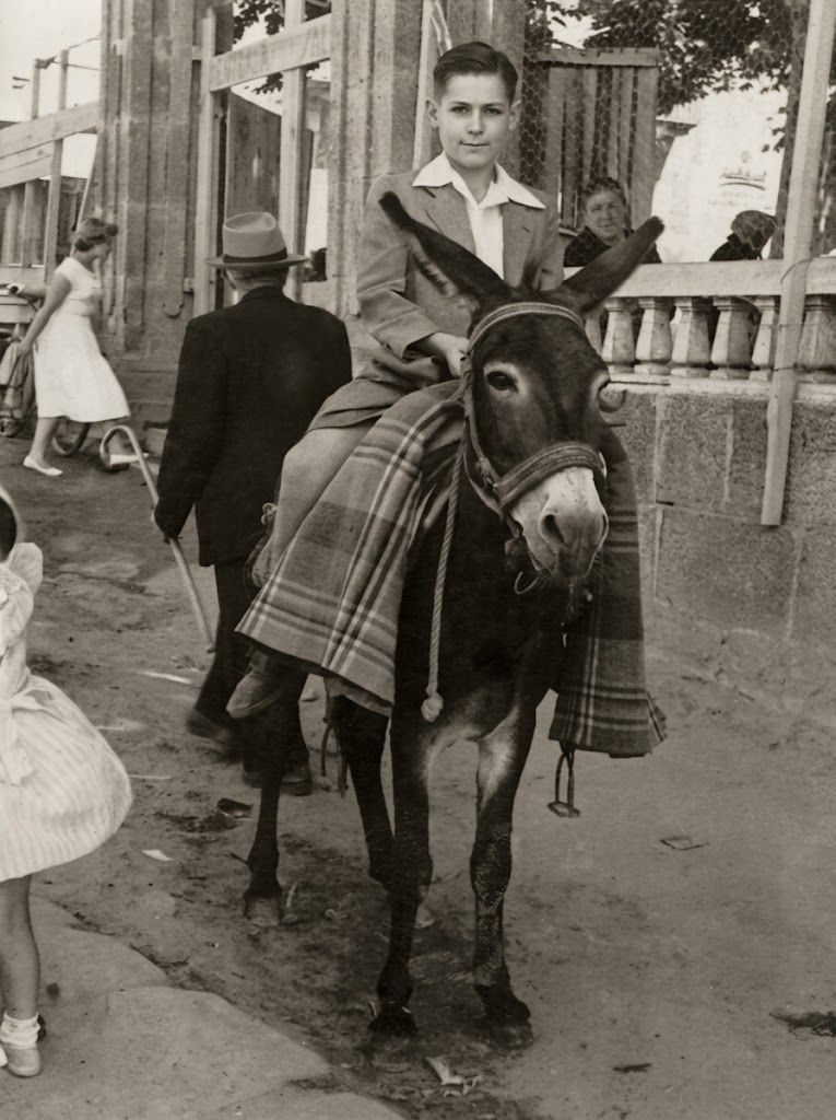 An old sepia photo of young Luis in a jacket, riding a donkey