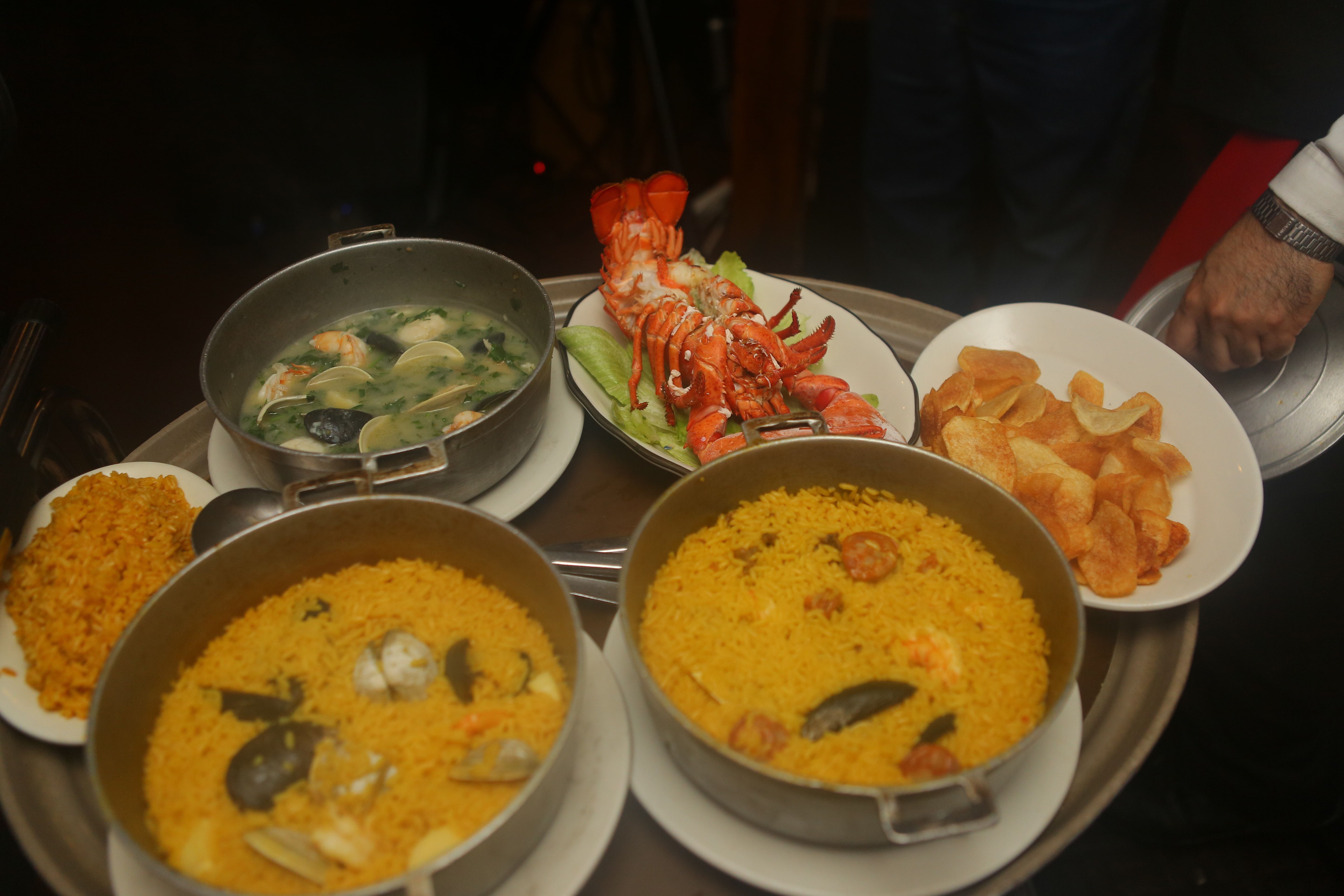 Paellas and a broiled lobster spread across a table at Casa Luis
